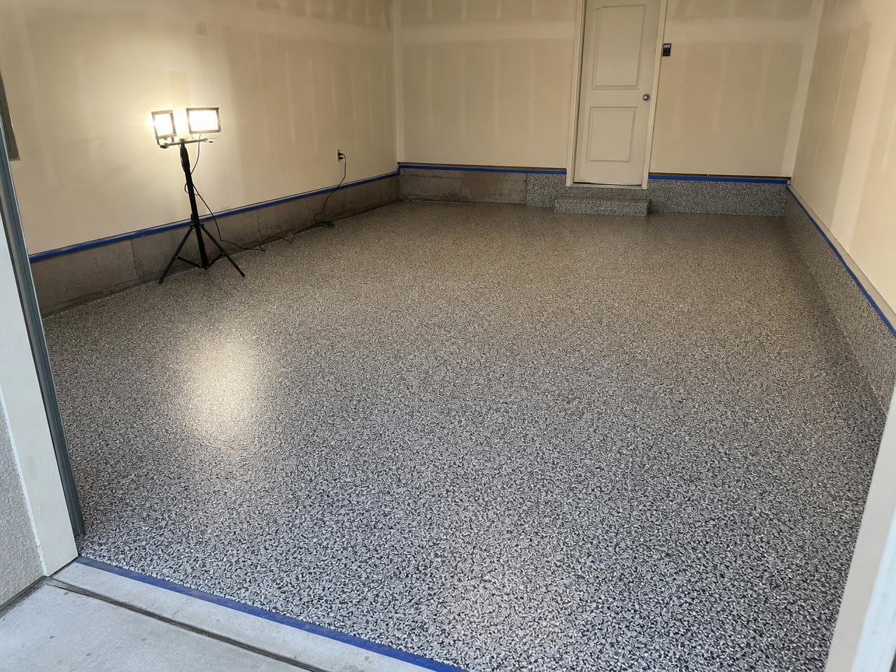 Garage mid install with freshly broadcast flake coating and taped wall coving