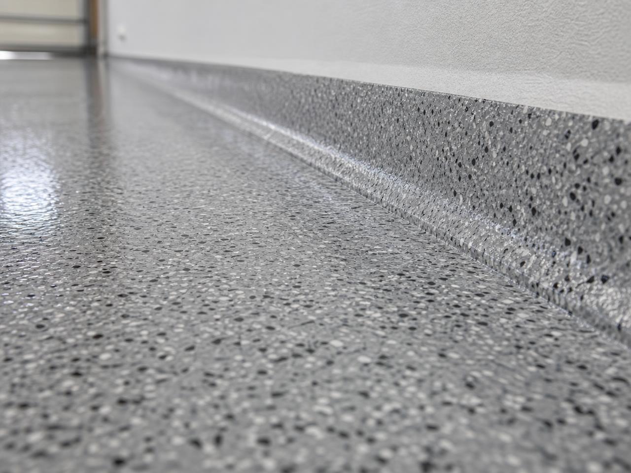 Close-up of gray flake coating meeting a crisp coved garage wall edge
