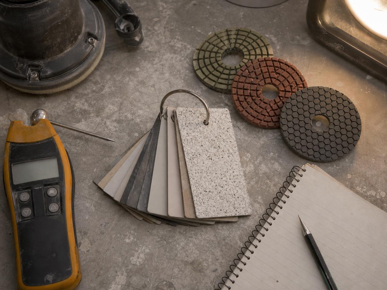 Moisture meter, coating sample chips, and grinding pads on a contractor workbench