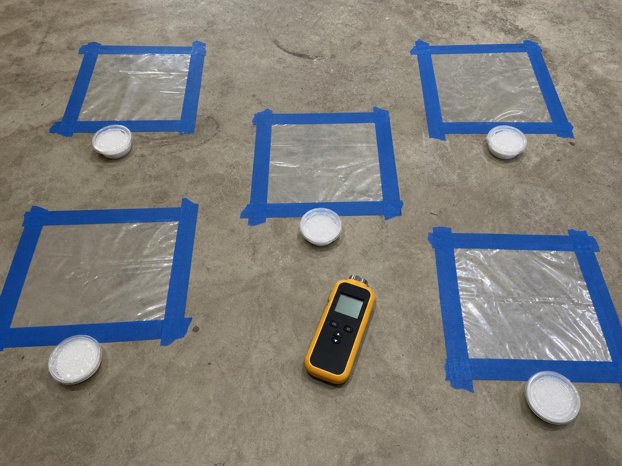 Calcium chloride test kits and taped plastic sheets on a bare concrete slab